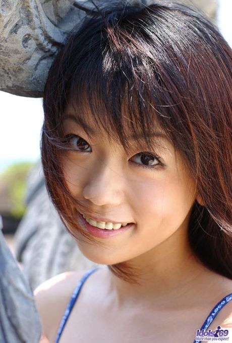 Lovely Japanese model smiles as she poses in her bikini on the beach